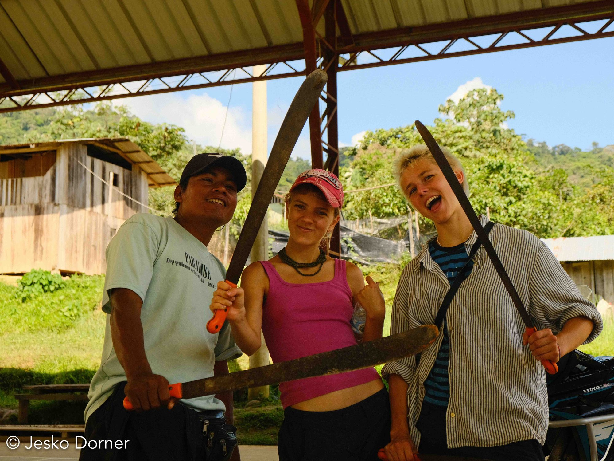 Voluntarias con machetes junto a un miembro de la comunidad